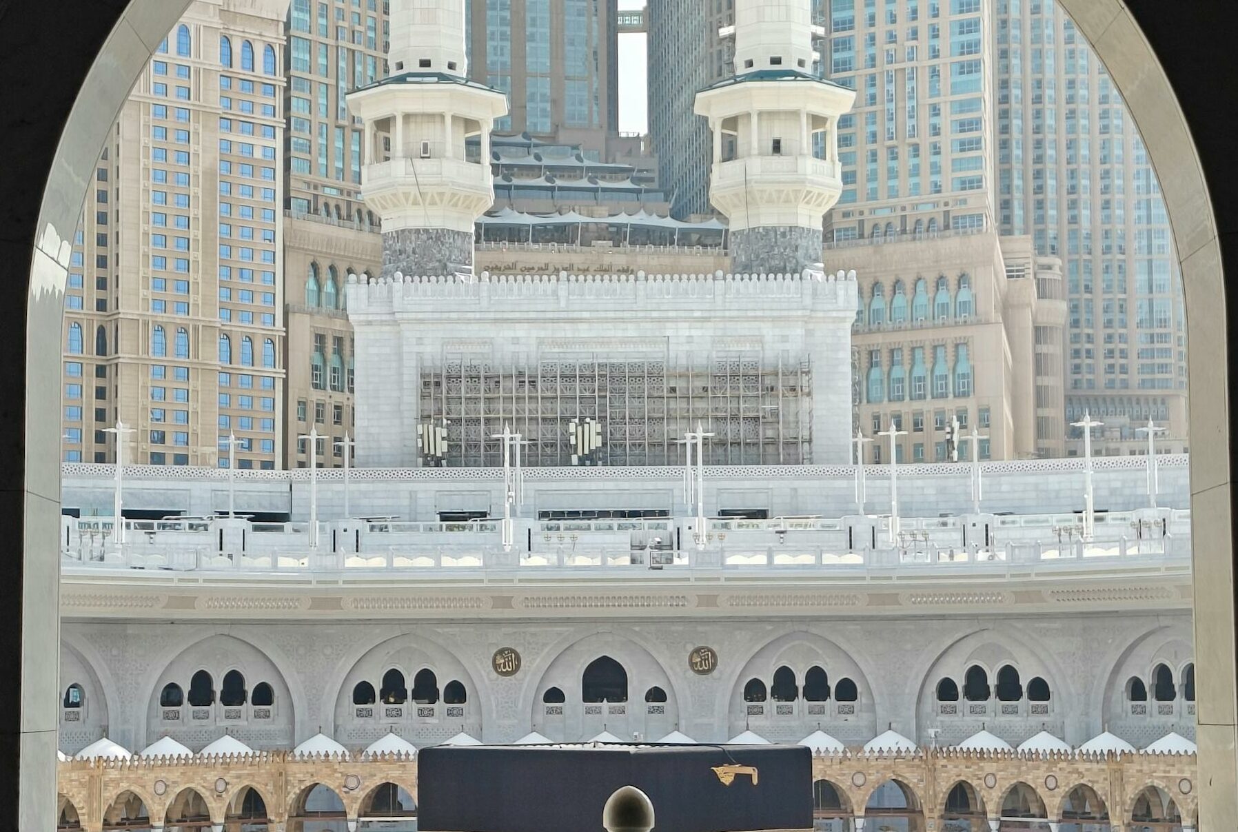 Captivating view of the Grand Mosque in Mecca, Saudi Arabia through a decorative arch, emphasizing the holy Kaaba.