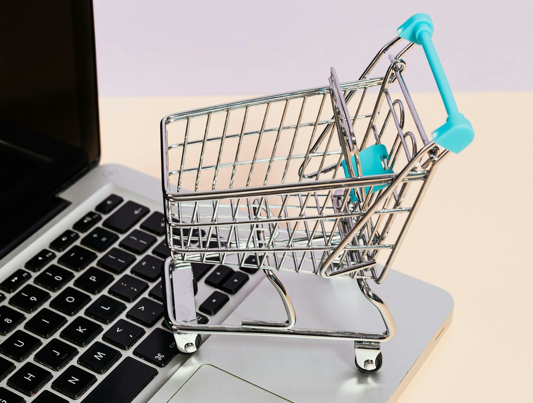 Mini shopping cart on a laptop symbolizes online shopping and e-commerce themes.
