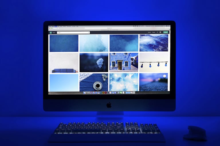 Modern workspace with a glowing blue theme and a computer monitor showcasing a gallery of images.