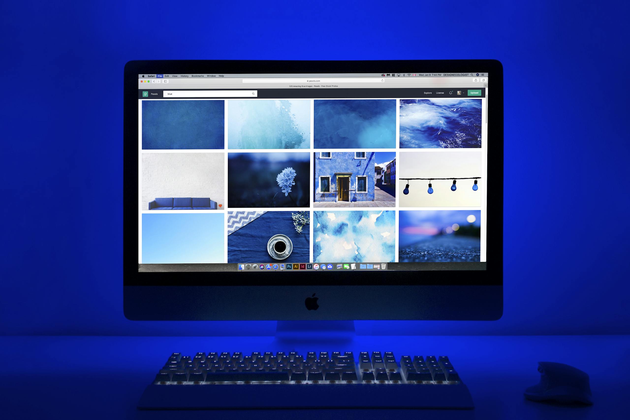 Modern workspace with a glowing blue theme and a computer monitor showcasing a gallery of images.