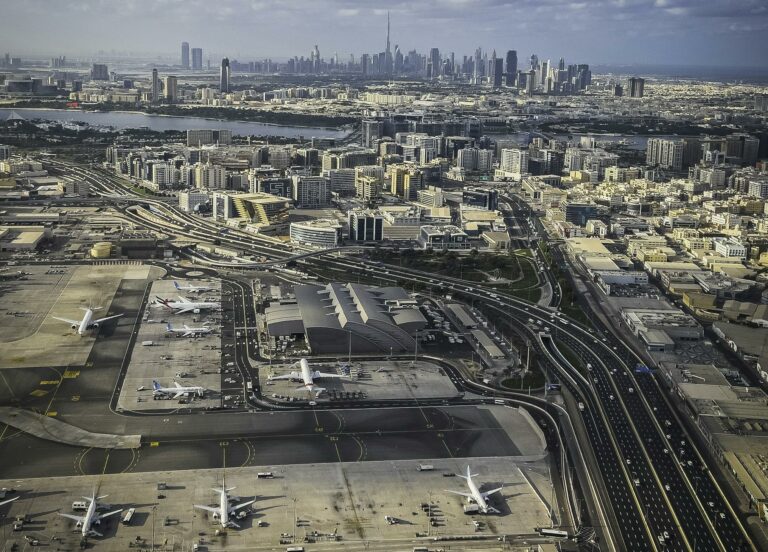 Stunning aerial view of Dubai cityscape with an airport in the foreground and skyscrapers in the distance.