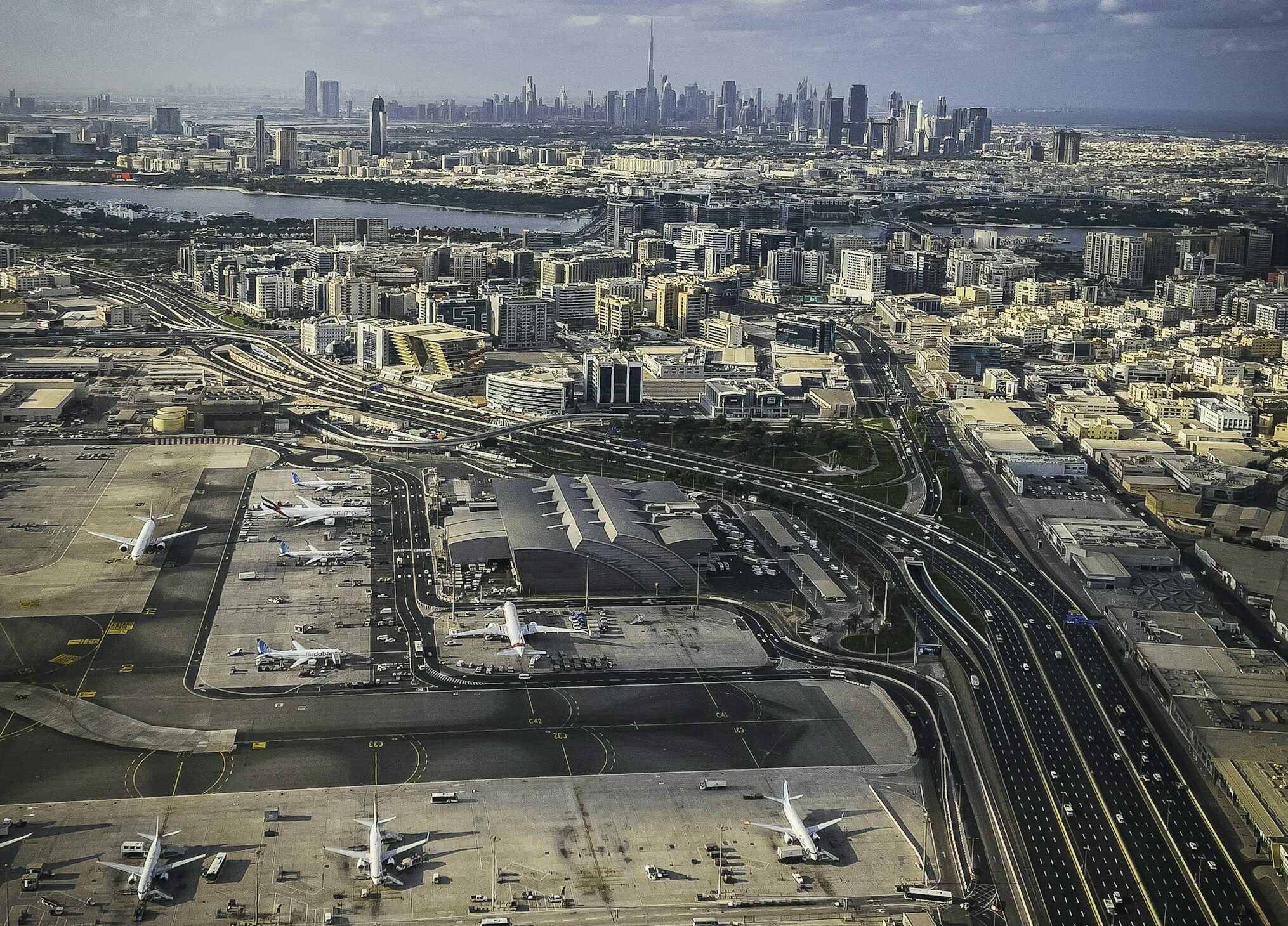 Stunning aerial view of Dubai cityscape with an airport in the foreground and skyscrapers in the distance.