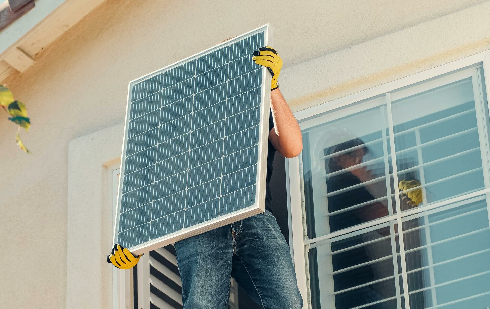Technician carrying a solar panel on a rooftop for installation, promoting renewable energy.
