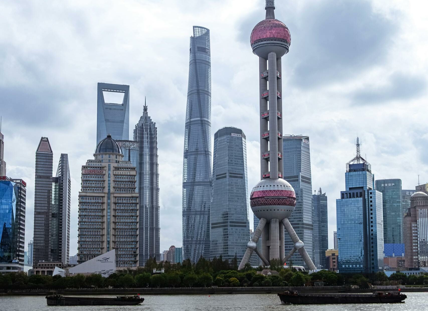 View of Shanghai's modern skyline with the iconic Oriental Pearl Tower under a cloudy sky.