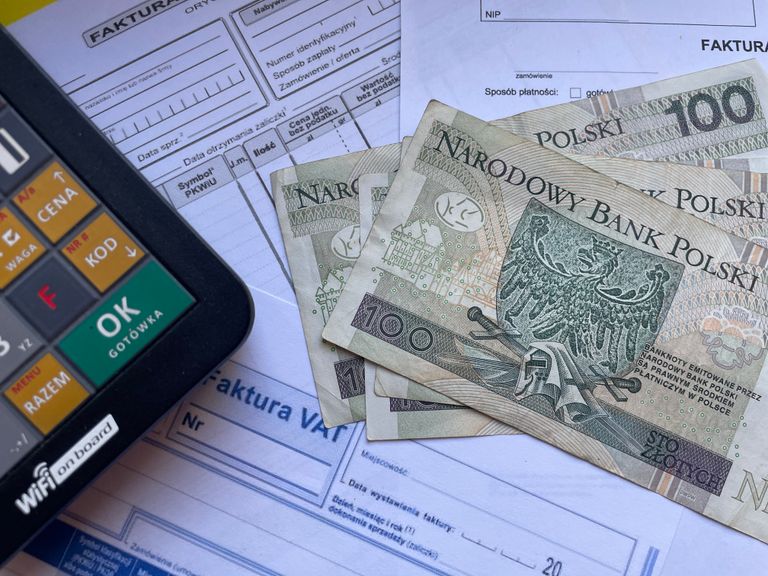 Polish currency placed on invoices with a calculator, illustrating financial transactions or budgeting.